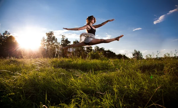 Girl doing split while jumping on field — Stock Photo, Image