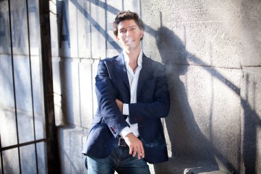 adam mavi ceket ve duman sigara duvara yaslanmış