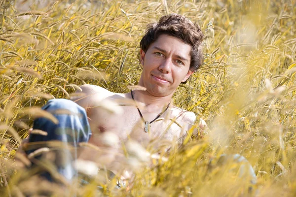 Man met naakte torso liggen in het hoge gras — Stockfoto