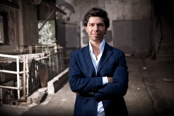 Man in jacket posing against grungy background on street — Stock Photo, Image