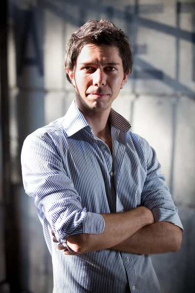 Stylish man in blue shirt posing on street with crossed arms — Stock Photo, Image