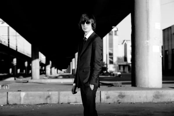 Man in suit wearing glasses against grunge city landscape — Stock Photo, Image