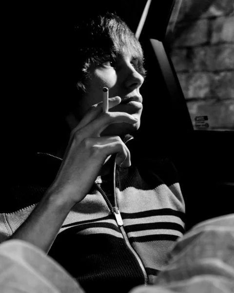 Мужчина курит сигарету в машине и смотрит в окно — стоковое фото