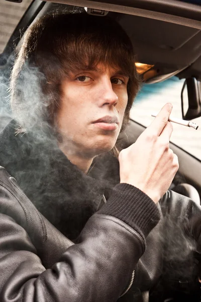 Homem de casaco fumando cigarro enquanto sentado no banco do passageiro — Fotografia de Stock