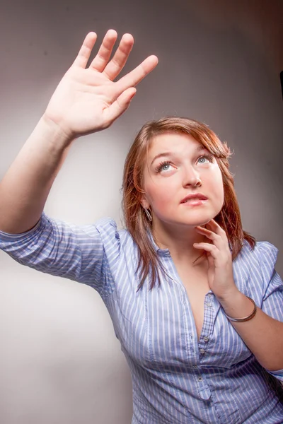 Brünettes Mädchen im blauen Hemd hält die Hand hoch und versteckt sich vor Licht — Stockfoto