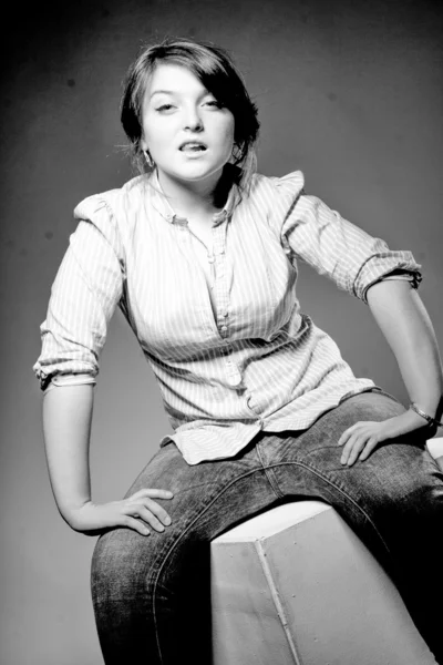 Mujer con gran pecho en camisa y jeans sentados en cubo blanco — Foto de Stock