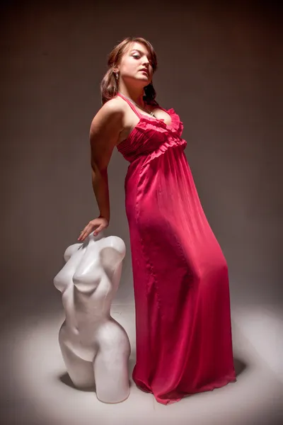 Beyaz manken kılığında Kırmızı elbiseli esmer kadın — Stok fotoğraf