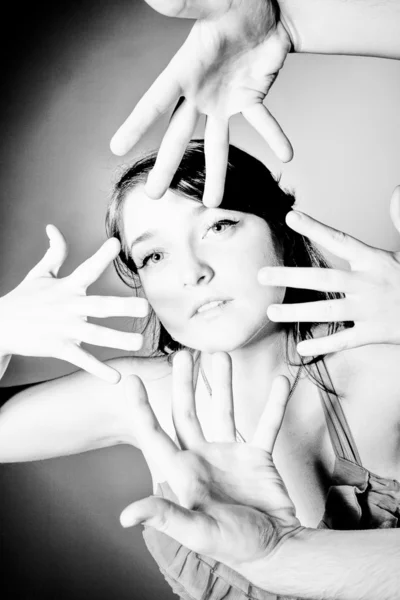 Portrait of brunette girl surrounded by four hands — Stock Photo, Image