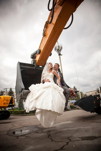 这对新婚的夫妇坐在推土机铲斗 — 图库照片