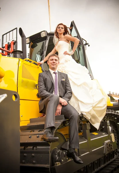 Coppia sposata posa su bulldozer giallo — Foto Stock