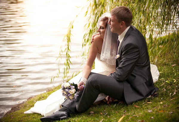 Pareja casada sentada en la orilla del río y mirando el agua —  Fotos de Stock