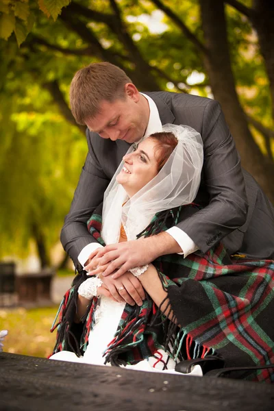 Handsome groom covering with plaid bride on summer terrace — Stock Photo, Image