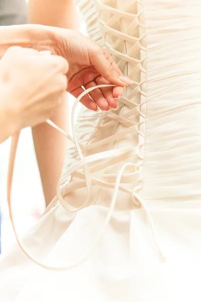 Photo of hands tying ribbon on brides corset — Stock Photo, Image