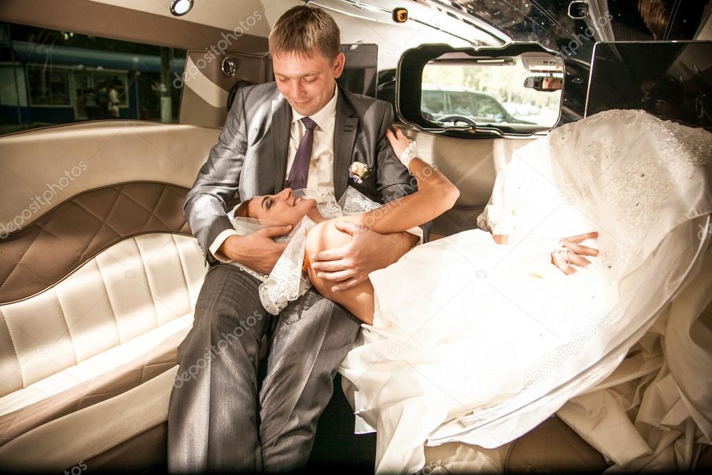 Bride lying on grooms legs on limousines back seat
