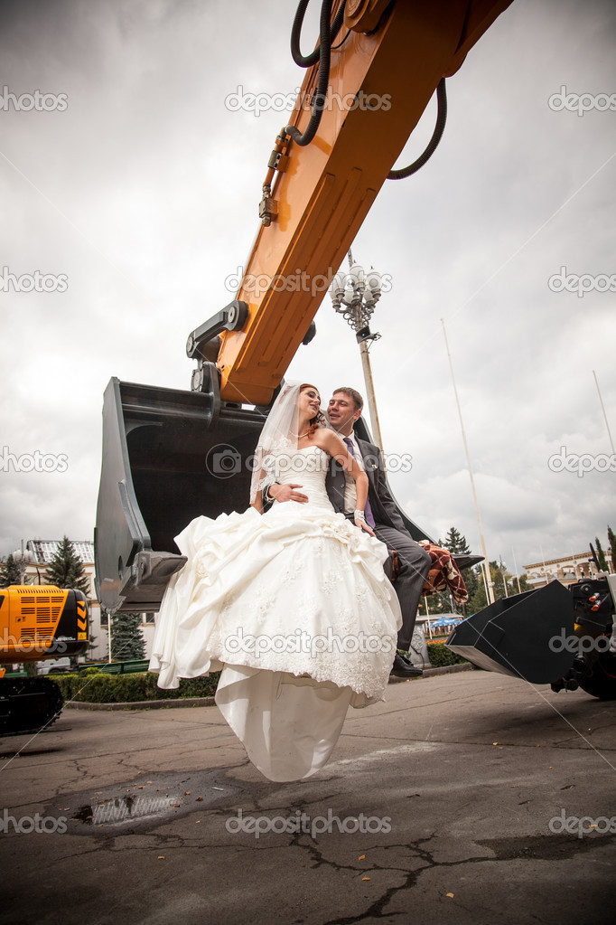 Newly married couple sitting in bulldozers bucket