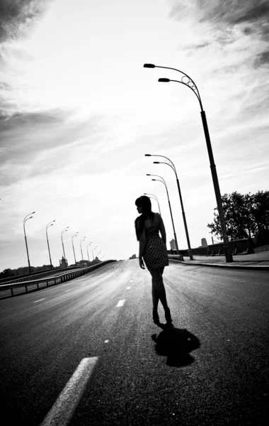 Silhouette photo of woman walking on empty highway — Stock Photo, Image