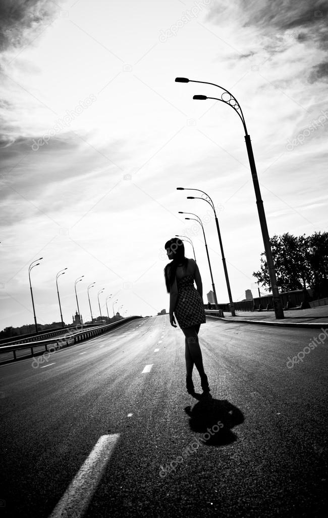 Silhouette photo of woman walking on empty highway