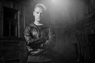 kızgın adam içinde deri ceket karşı eski bina poz.