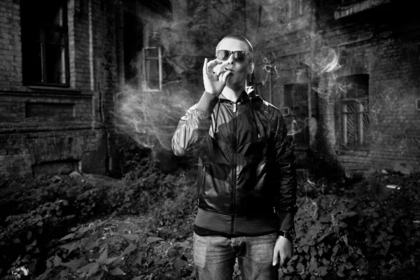 Retrato de un joven fumando marihuana contra un edificio antiguo — Foto de Stock