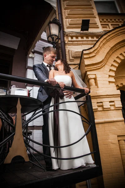 Novomanželům pár objímat na balkony, budovy — Stock fotografie