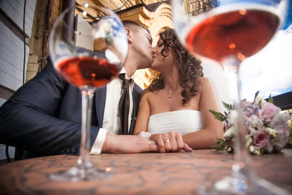 Portrait through glasses of dating couple kissing in restaurant — Stock Photo, Image