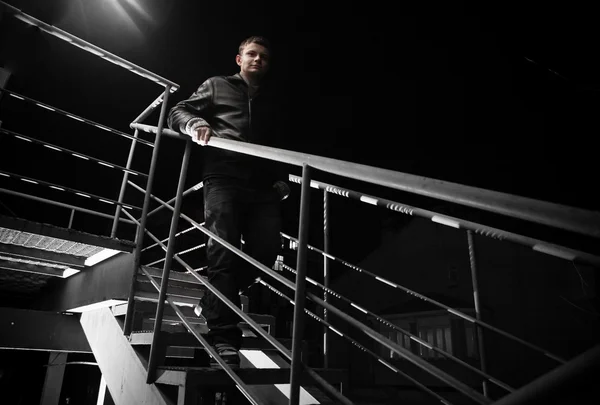 Homme en manteau de cuir descendant l'escalier la nuit — Photo