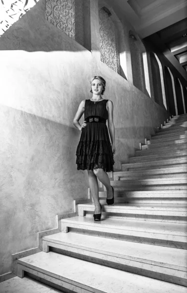 Elegant woman in short dress walking down marble stairs — Stock Photo, Image