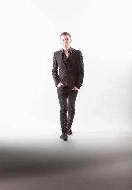 Elleri ceplerinde Studio ile yürüyen siyah elbiseli adam