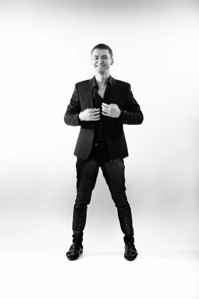 Young man in black suit standing at studio and laughing — Stock Photo, Image