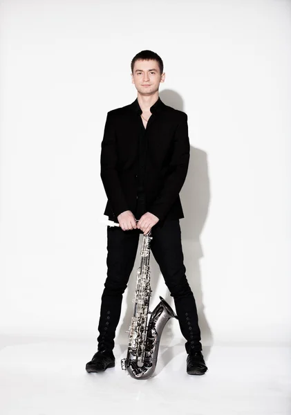 Man in black suit standing with saxophone at studio — Stock Photo, Image