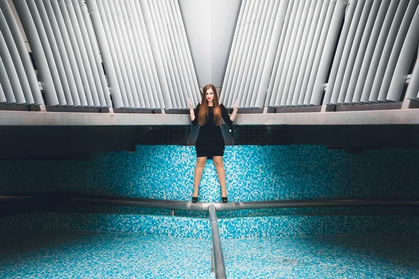 Mujer en vestido negro posando en fuente vacía con azulejo azul — Foto de Stock