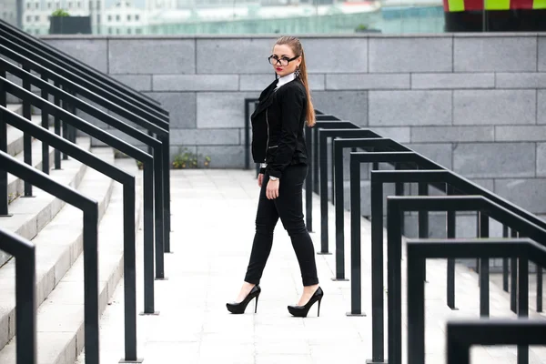 Woman in black suit walking on stairs with railings at street — Stock Photo, Image