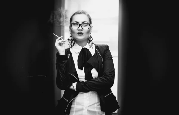 Woman in glasses smoking cigarette outdoor against city view — Stock Photo, Image