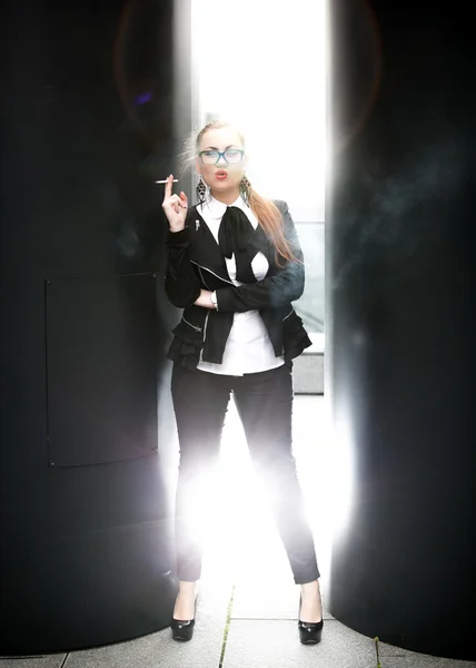 Frau im klassischen Anzug raucht Zigarette gegen Straßenansicht — Stockfoto