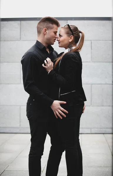 在大街上抱着的黑色衣服的年轻性感夫妇 — 图库照片