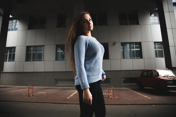 Woman in blue sweater walking on street and looking over shoulder — Stock Photo, Image