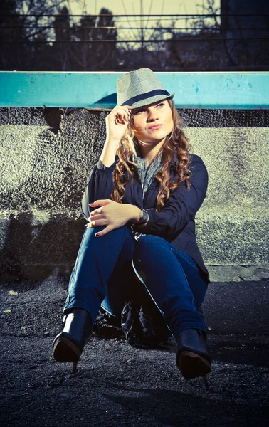 Foto van sexy vrouw in jeans en hoed zittend op dak — Stockfoto