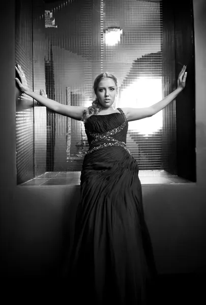 Woman in black dress sitting against big mirror on wall — Stock Photo, Image