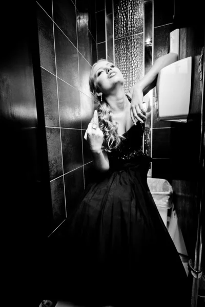 Sexy Frau im Kleid sitzt auf Toilette und zeigt Mittelfinger — Stockfoto