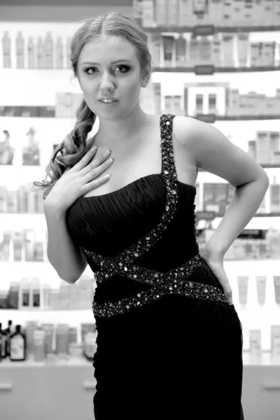 Woman in black dress standing against shelves in drugstore — Stock Photo, Image