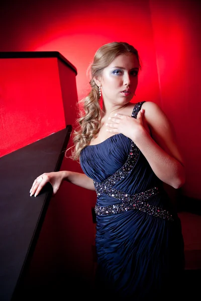 Sexy woman in evening dress posing against red background — Stock Photo, Image