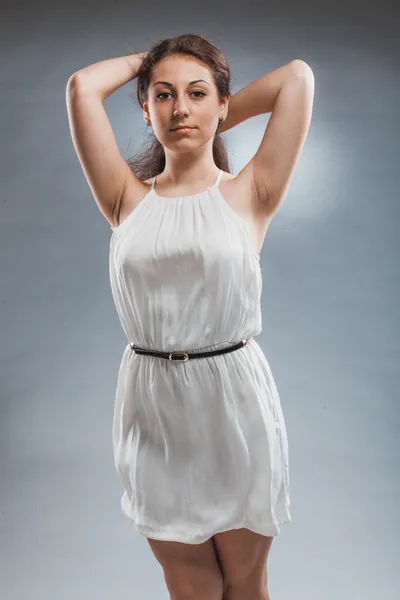 Sexy woman in white tunic holding hands on head — Stock Photo, Image