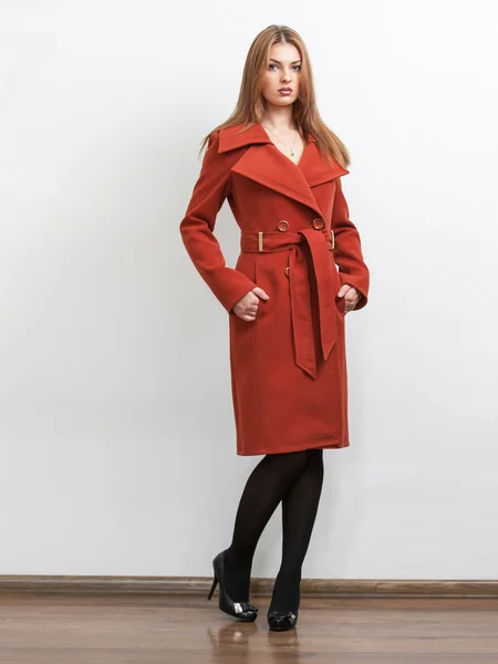 Slim model wearing long red coat in studio — Stock Photo, Image