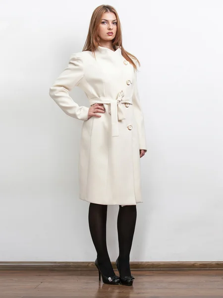 Mulher vestindo casaco longo clássico branco e segurando a mão na cintura — Fotografia de Stock