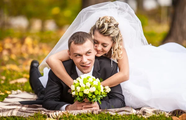 Frisch verheiratetes Paar liegt auf Gras im Park und hat Spaß — Stockfoto
