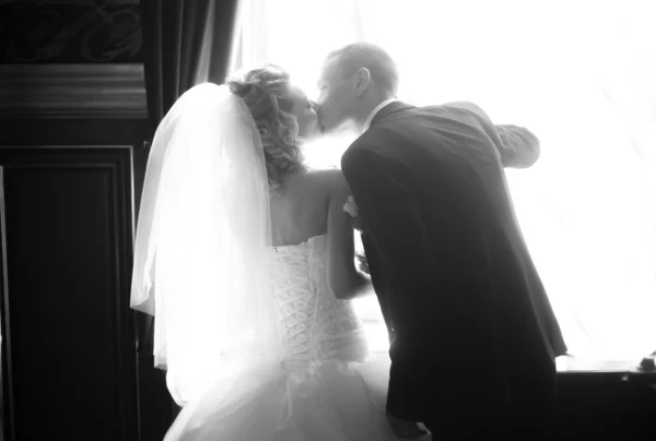 Bride and groom kissing passionately against big window — Stock Photo, Image