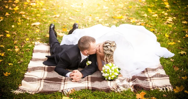 Casal casado deitado no parque em xadrez e beijando apaixonadamente — Fotografia de Stock