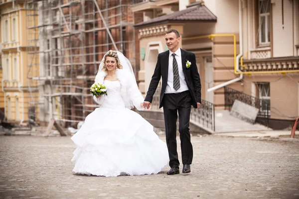 Bride and groom holding hands and walking in old city — Stock Photo, Image
