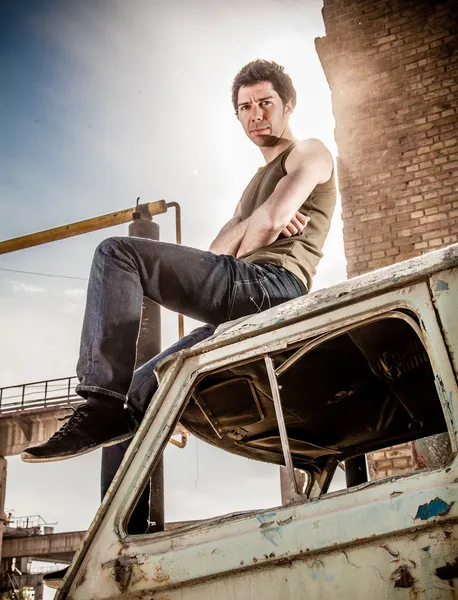 Людина в синглеті і джинсах, що сидить на даху старого мікроавтобуса — стокове фото