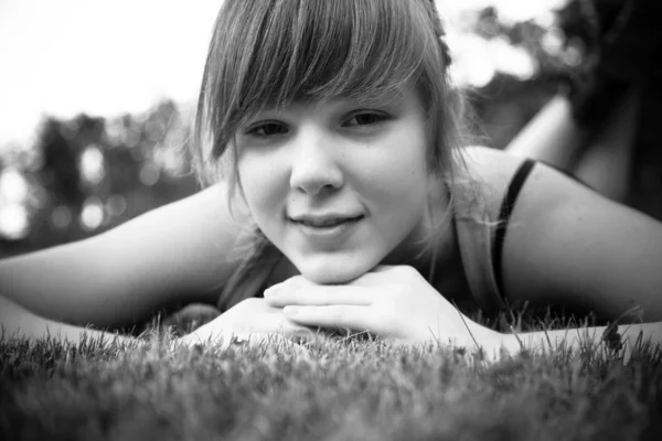 Closeup portrait of young woman lying on lawn on stomach — Stock Photo, Image